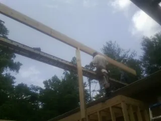 Carpenter setting a ridge beam over a new addition frame — Ice Dam Removal by Roofing Brothers in New Site