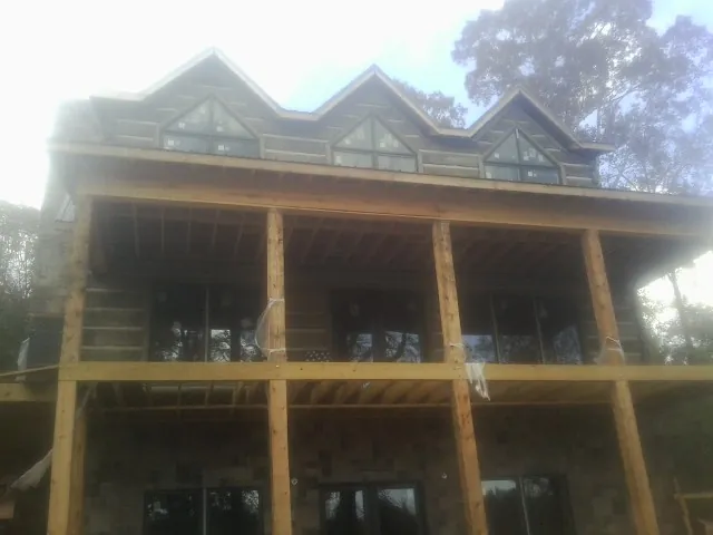 Dormers and porch framing on a large log home under construction — Roof Coating work by our crew in New Site