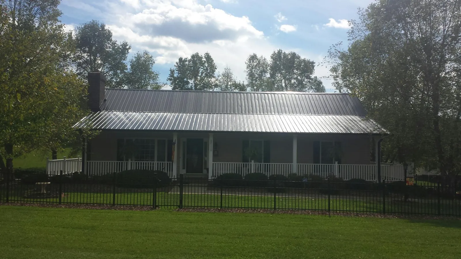 Gray metal roof on a brick ranch with a full width front porch — Gutter Guard Installation work by our crew in New Site