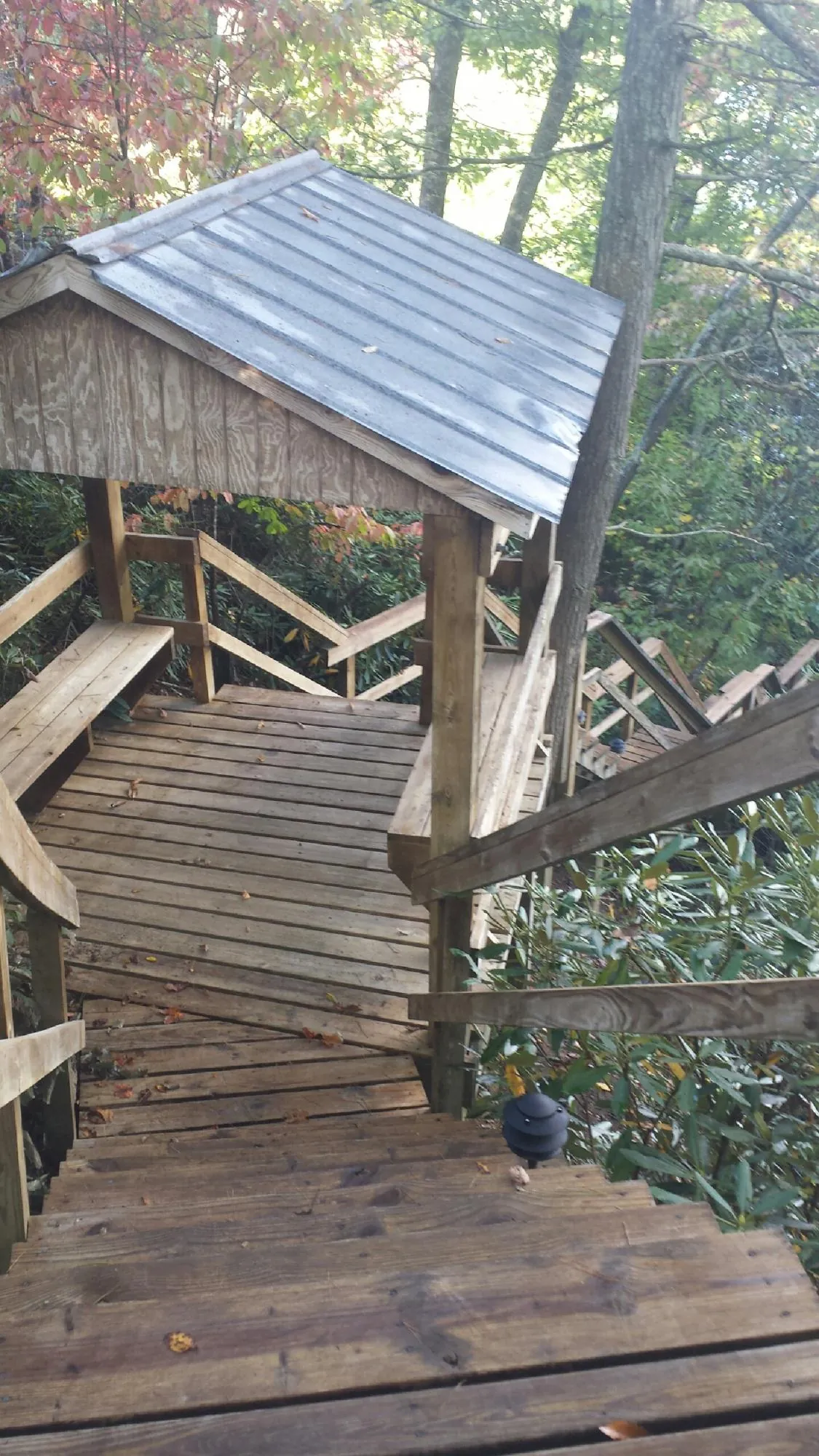 Metal roofed shelter over wooden steps on a wooded walkway — Skylight Repair & Installation work by our crew in New Site