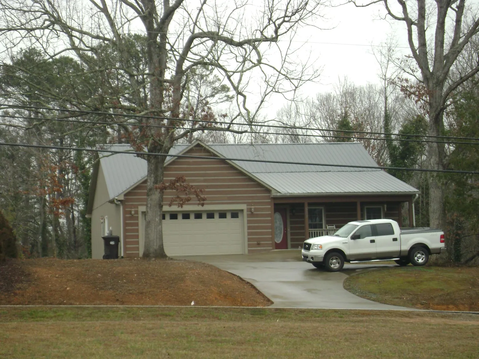 Gray metal roof on a log sided house with an attached two car garage in New Site