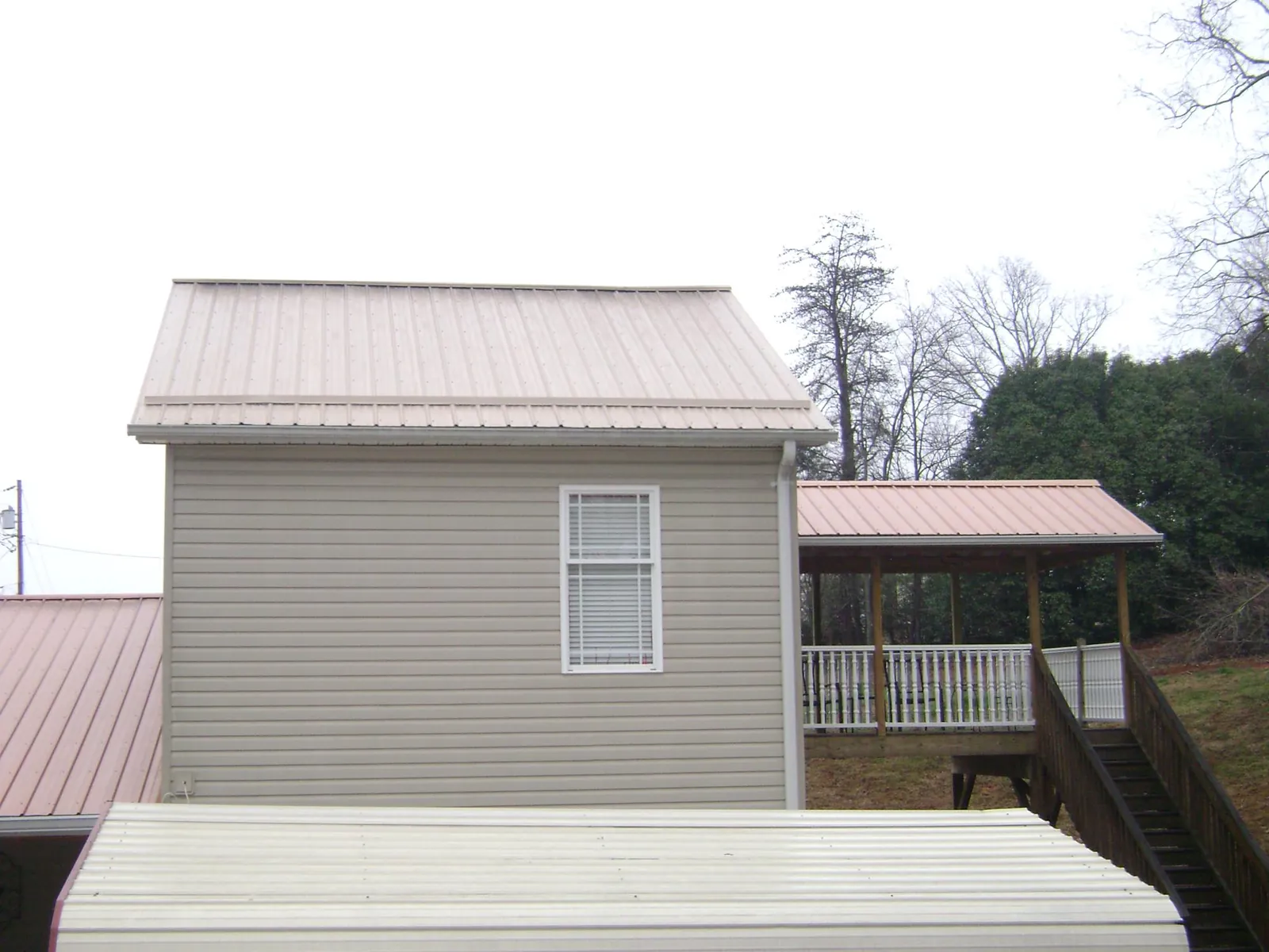 Tan metal roofs on a two story addition and attached porch, from a Roof Replacement job in New Site