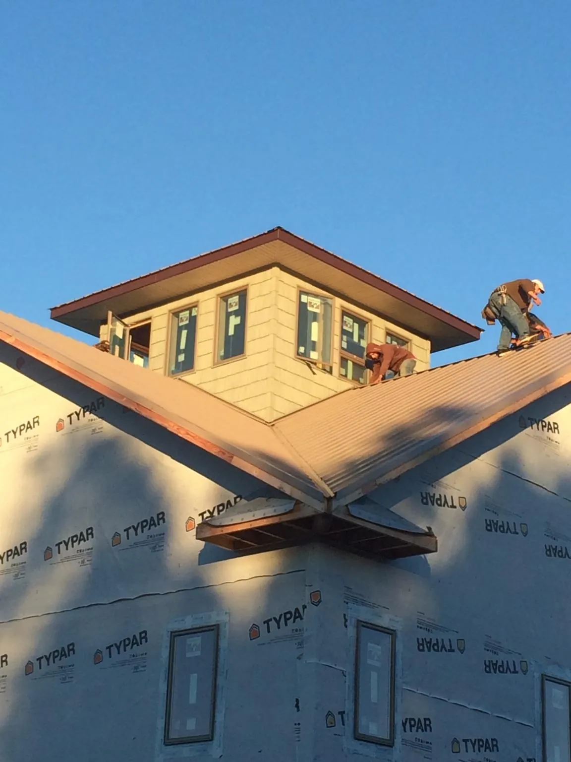 Roofers working around a rooftop cupola on a new metal roof at sunset — Roof Waterproofing in New Site by Roofing Brothers